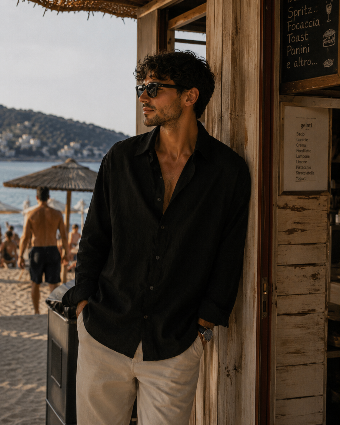 Uomo con camicia nera davanti a un chiosco sulla spiaggia